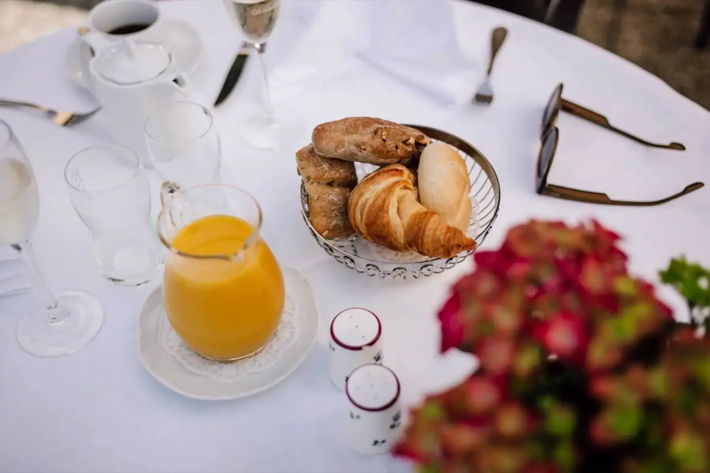 Gedeckter Frühstückstisch mit Orangensaft, Croissants und Kaffee