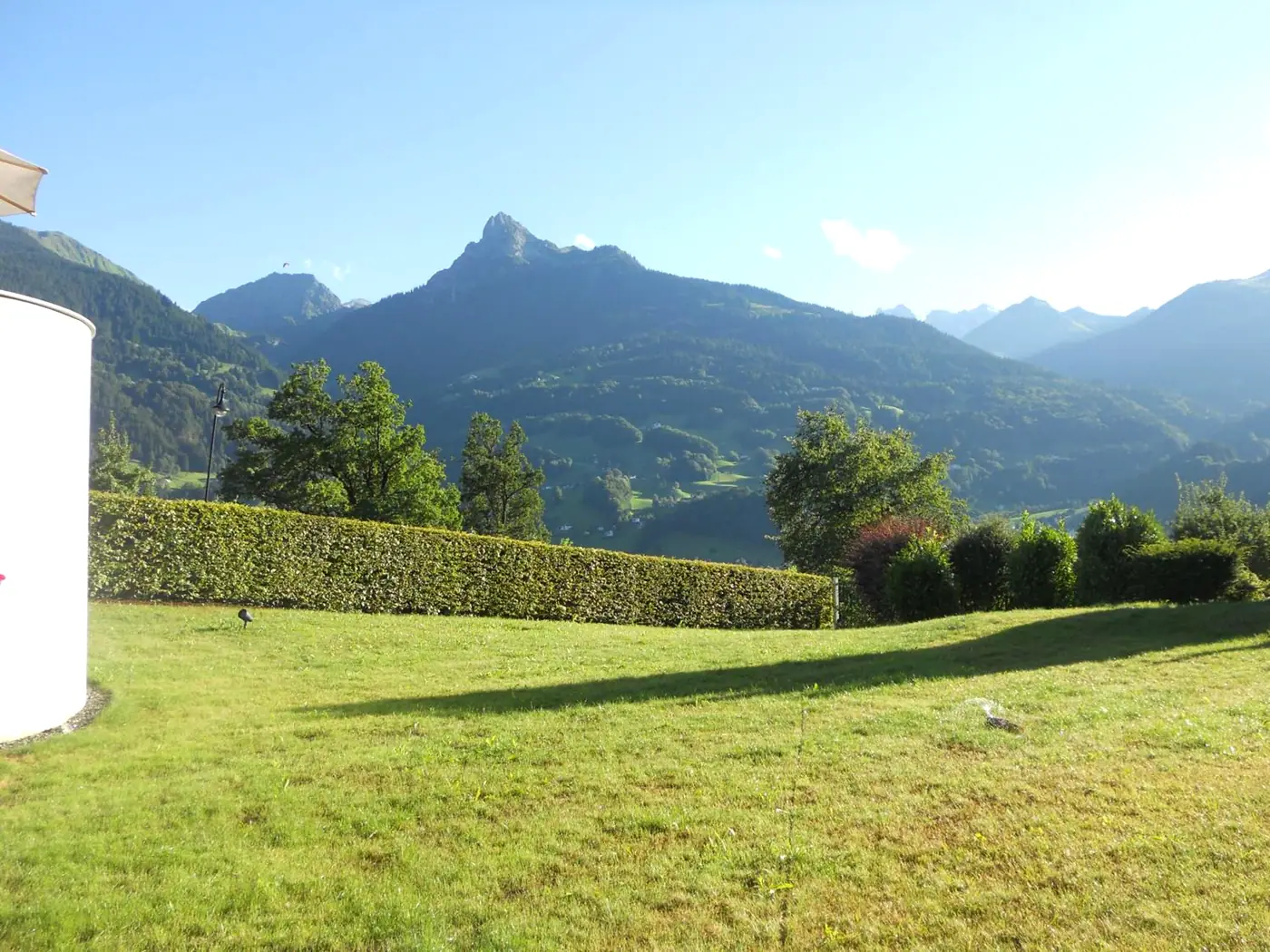 Garten mit Liegewiese, dahinter die Berge