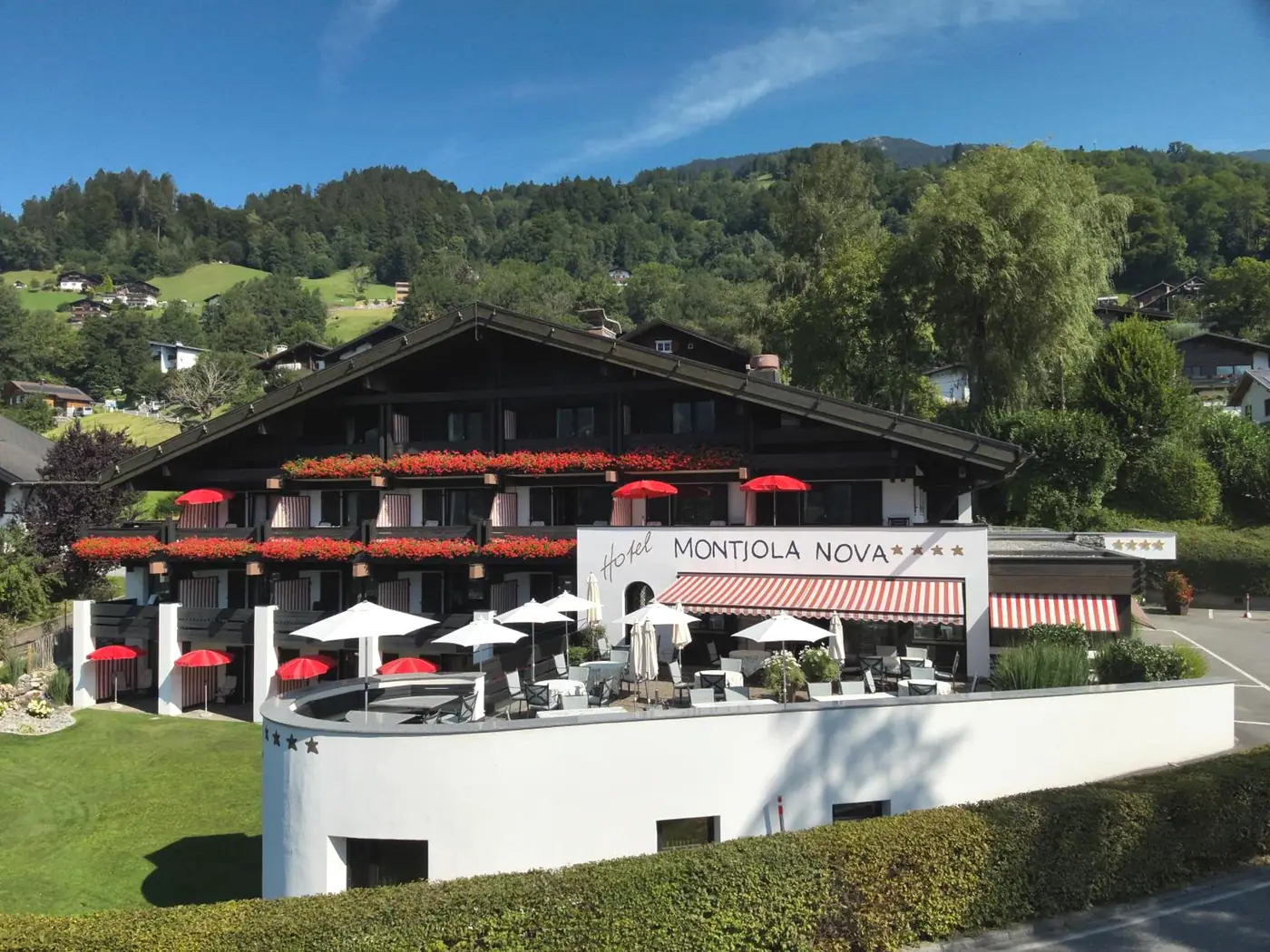 Das Hotel Montjola Nova im Sommer von oben, mit Blumen an den Balkonen und der runden Terrasse
