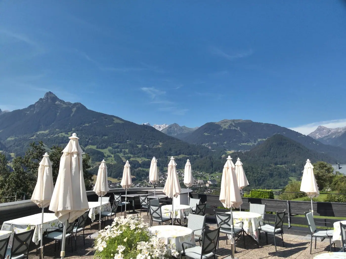 Terrasse mit weißen Schirmen am Morgen, dahinter die Zimba